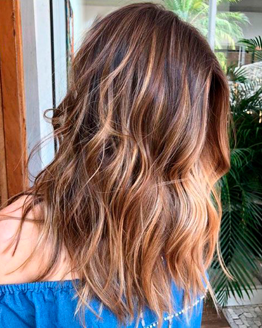 Mechas californianas caramelo suave en cabello castaño con ondas, efecto natural y cálido