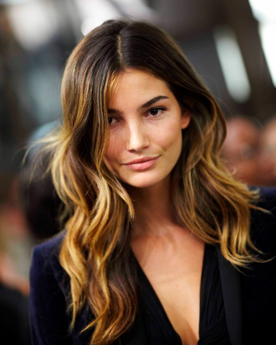 Mechas californianas en tonos cobre dorado sobre cabello castaño largo con ondas suaves