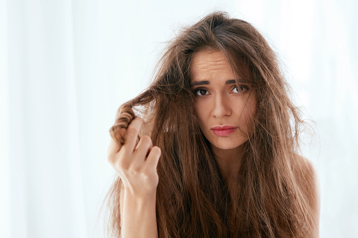 Mujer preocupada por el pelo seco y dañado por el verano